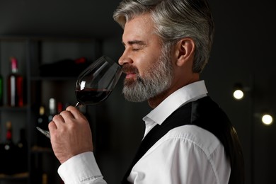 Professional sommelier tasting red wine in glass indoors