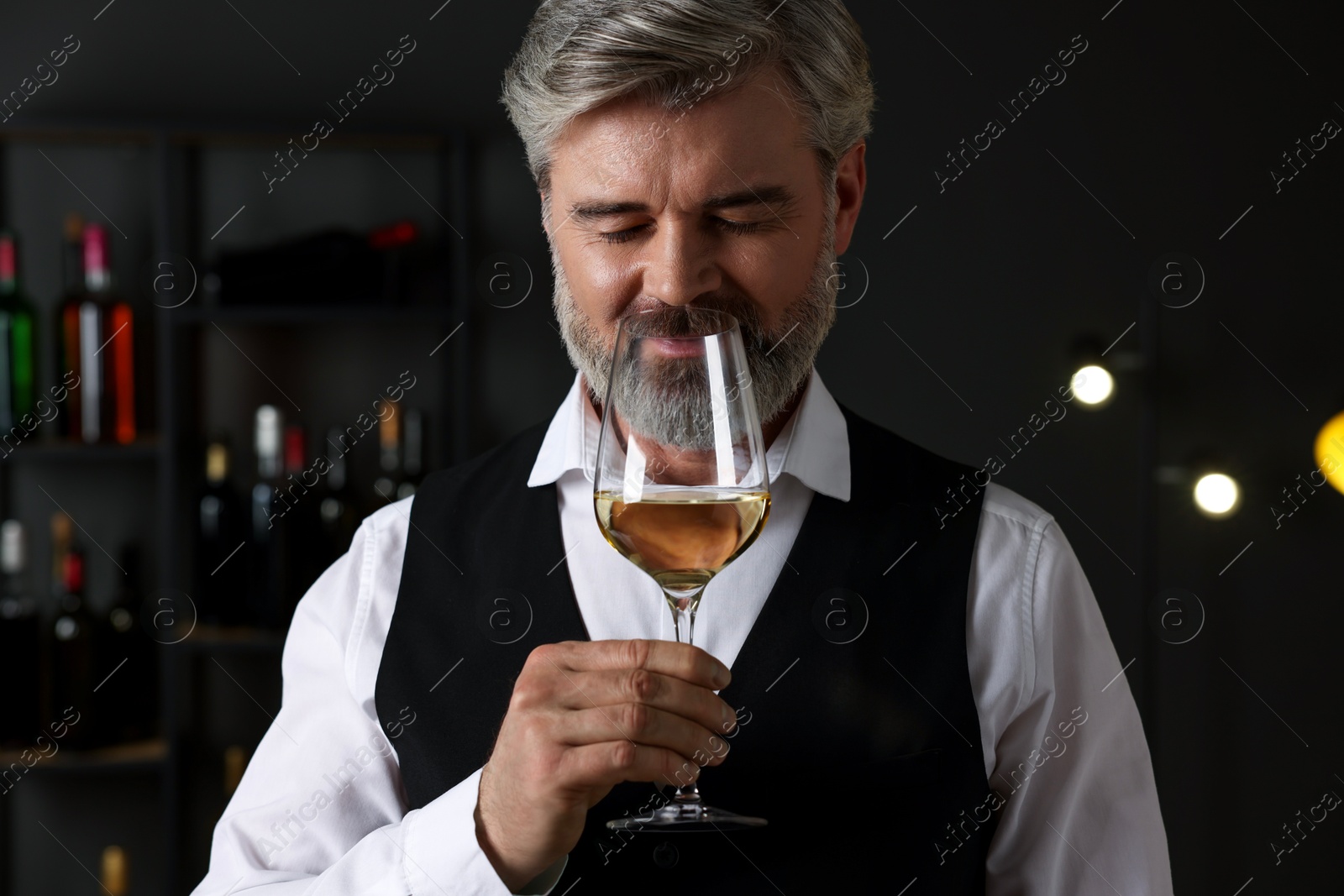 Photo of Professional sommelier tasting white wine in glass indoors