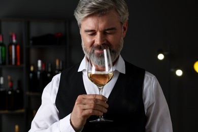 Professional sommelier tasting white wine in glass indoors