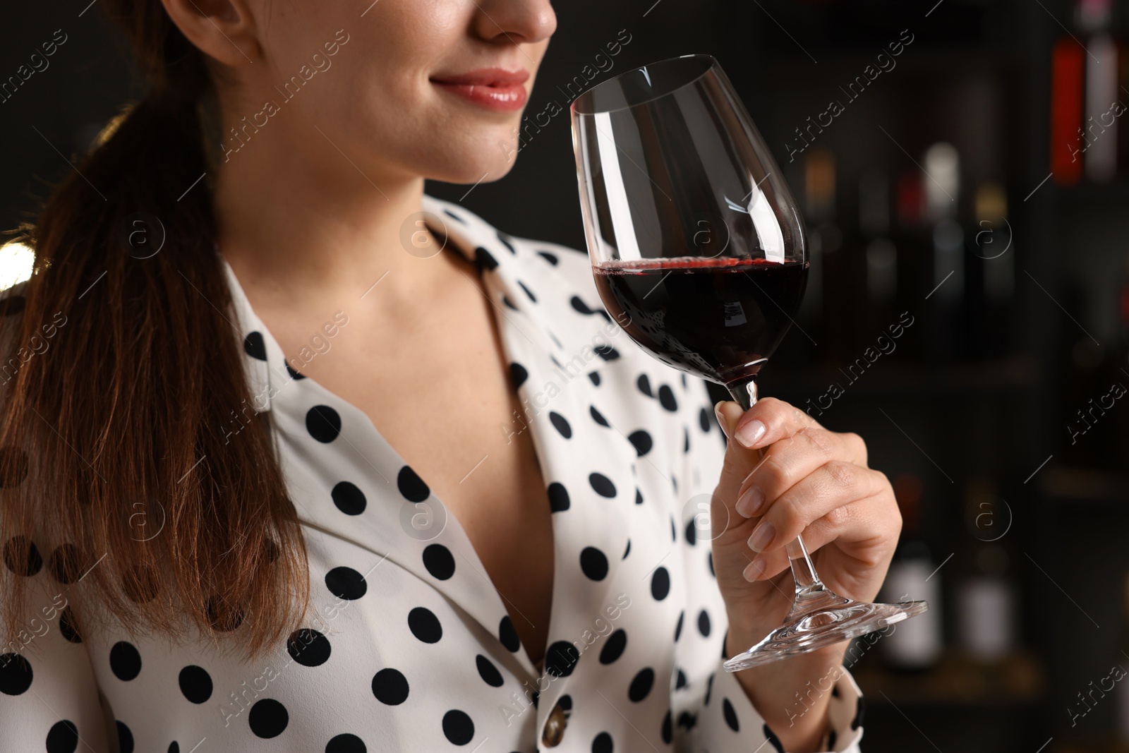 Photo of Professional sommelier tasting red wine in glass indoors, closeup