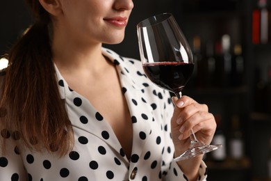 Professional sommelier tasting red wine in glass indoors, closeup