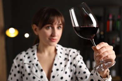 Photo of Professional sommelier analyzing quality of red wine indoors, selective focus