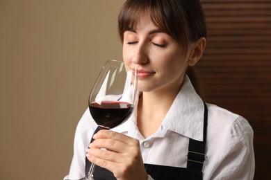 Photo of Professional sommelier tasting red wine in glass indoors