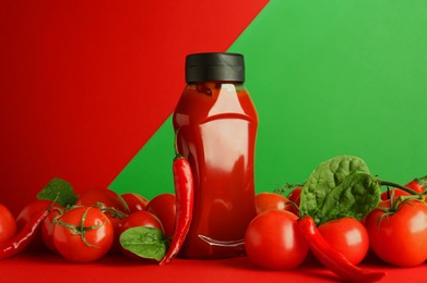 Photo of Ketchup, tomatoes, chili peppers and spinach on color background