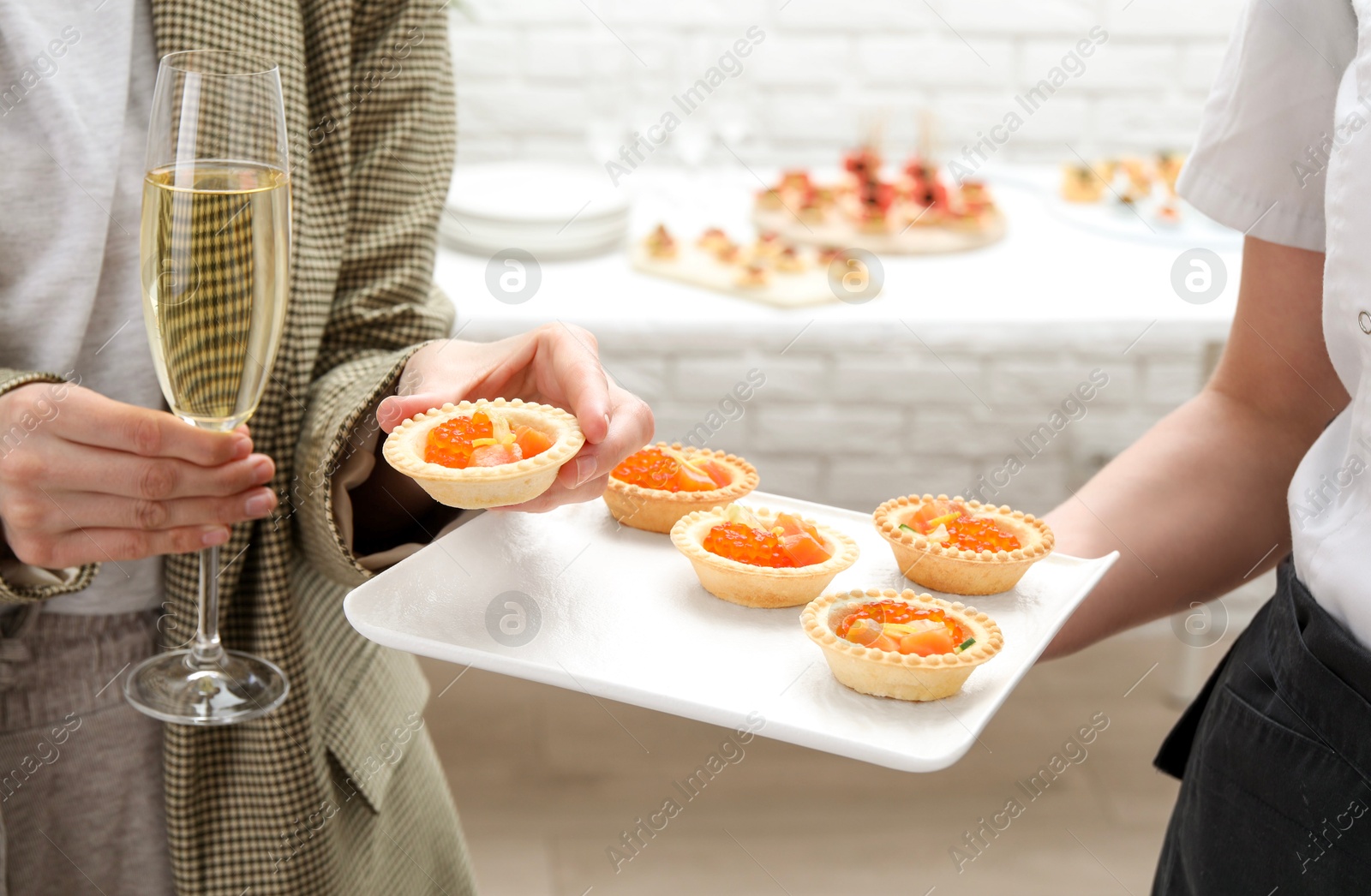 Photo of Woman taking tasty canape from waiter with board indoors, closeup