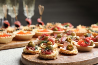 Photo of Many different tasty canapes and wine on white table, closeup