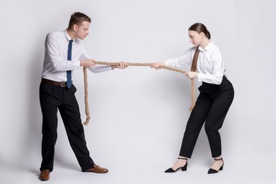 Photo of Competition concept. Businesspeople pulling rope on grey background