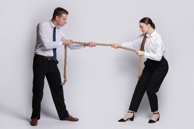 Competition concept. Businesspeople pulling rope on grey background