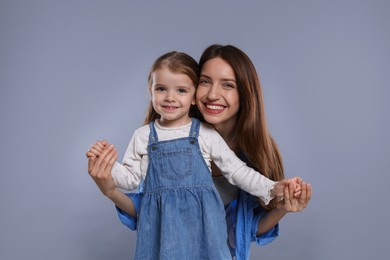 Photo of Portrait of happy mother with her cute little daughter on grey background