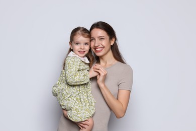 Photo of Portrait of happy mother with her cute little daughter on grey background