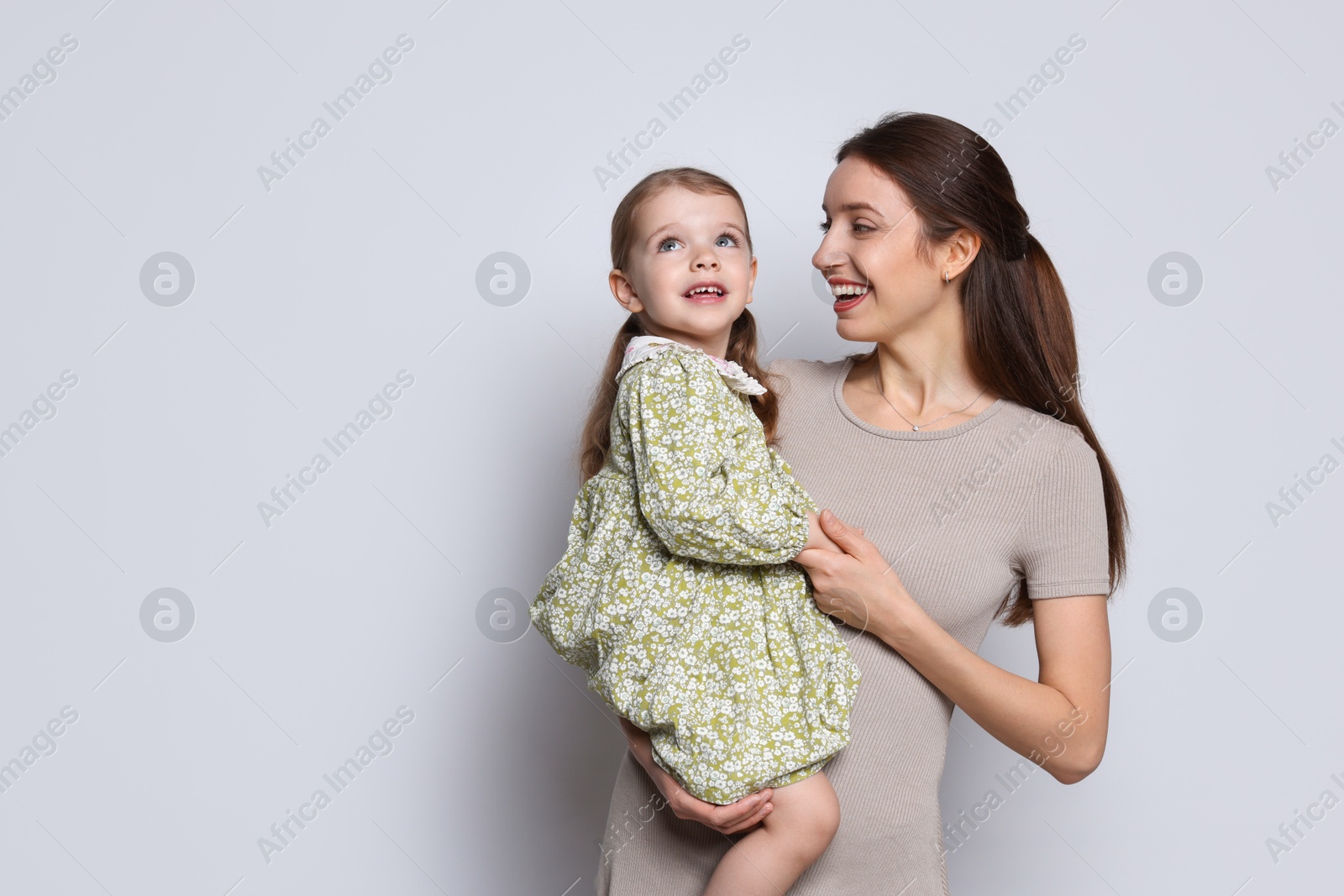 Photo of Happy mother with her cute little daughter on grey background, space for text