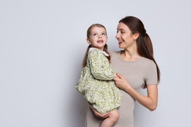 Photo of Happy mother with her cute little daughter on grey background, space for text