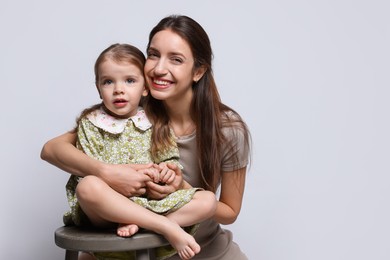 Photo of Portrait of happy mother with her cute little daughter on grey background, space for text