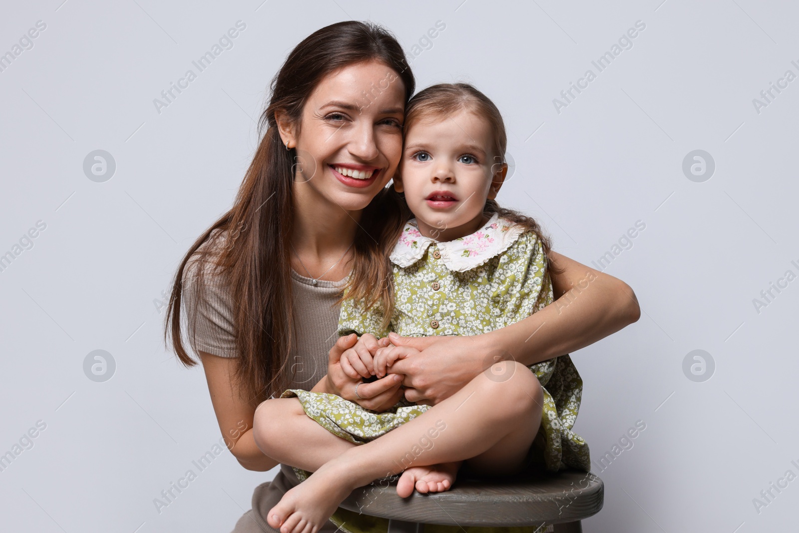 Photo of Portrait of happy mother with her cute little daughter on grey background