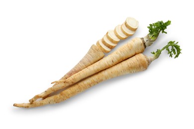 Photo of Whole and cut fresh parsley roots isolated on white, top view