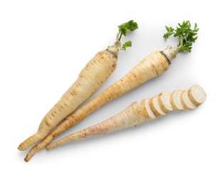 Photo of Whole and cut fresh parsley roots isolated on white, top view