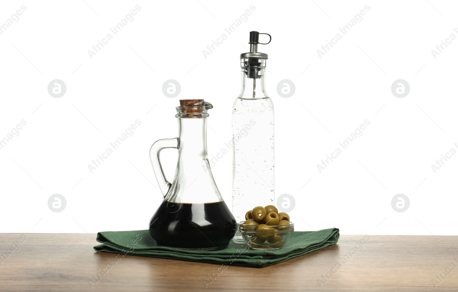 Photo of Vinegars in bottles and olives on wooden table against white background