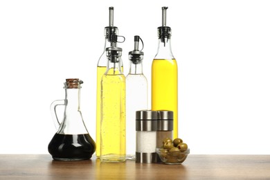 Photo of Salad dressings, olives and spices on wooden table against white background