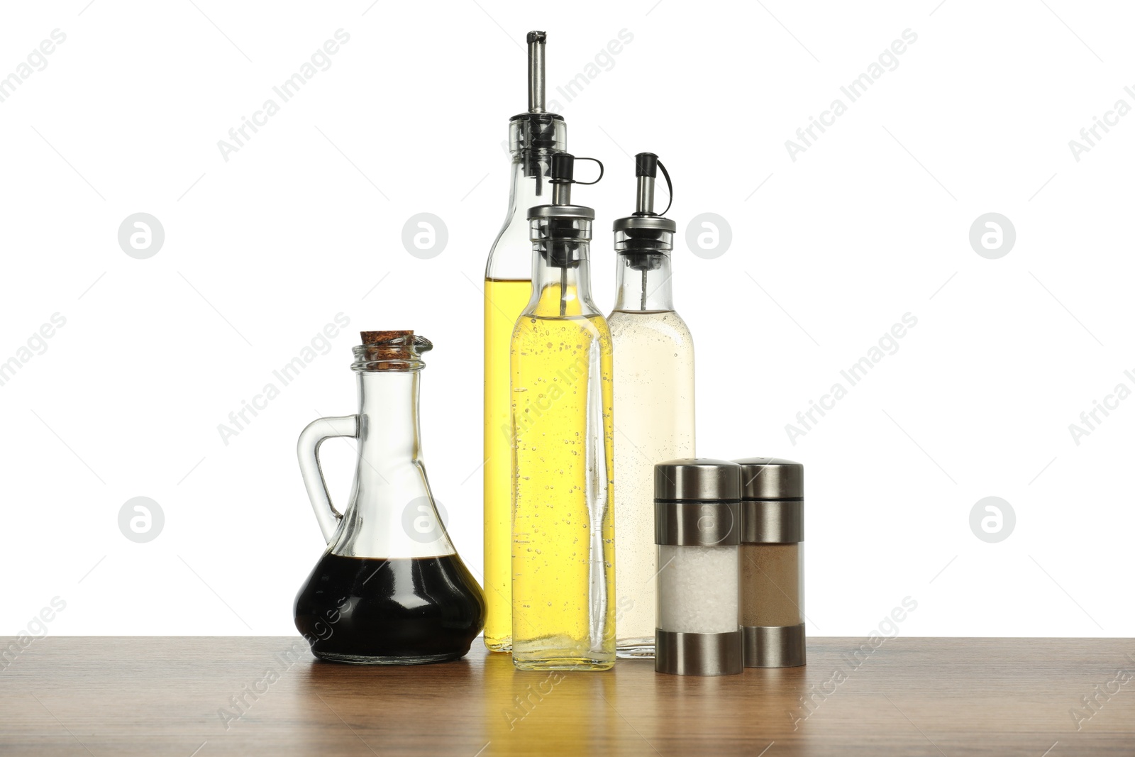 Photo of Salad dressings and spices on wooden table against white background