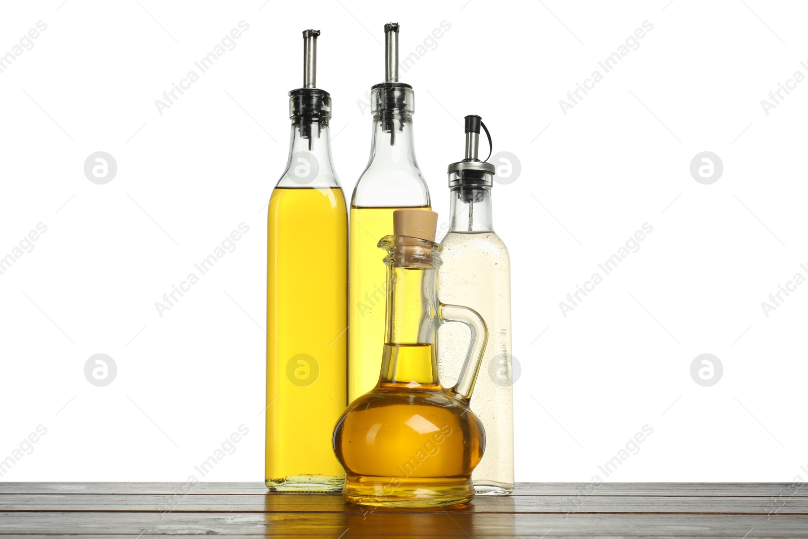 Photo of Oils and vinegar in bottles on wooden table against white background