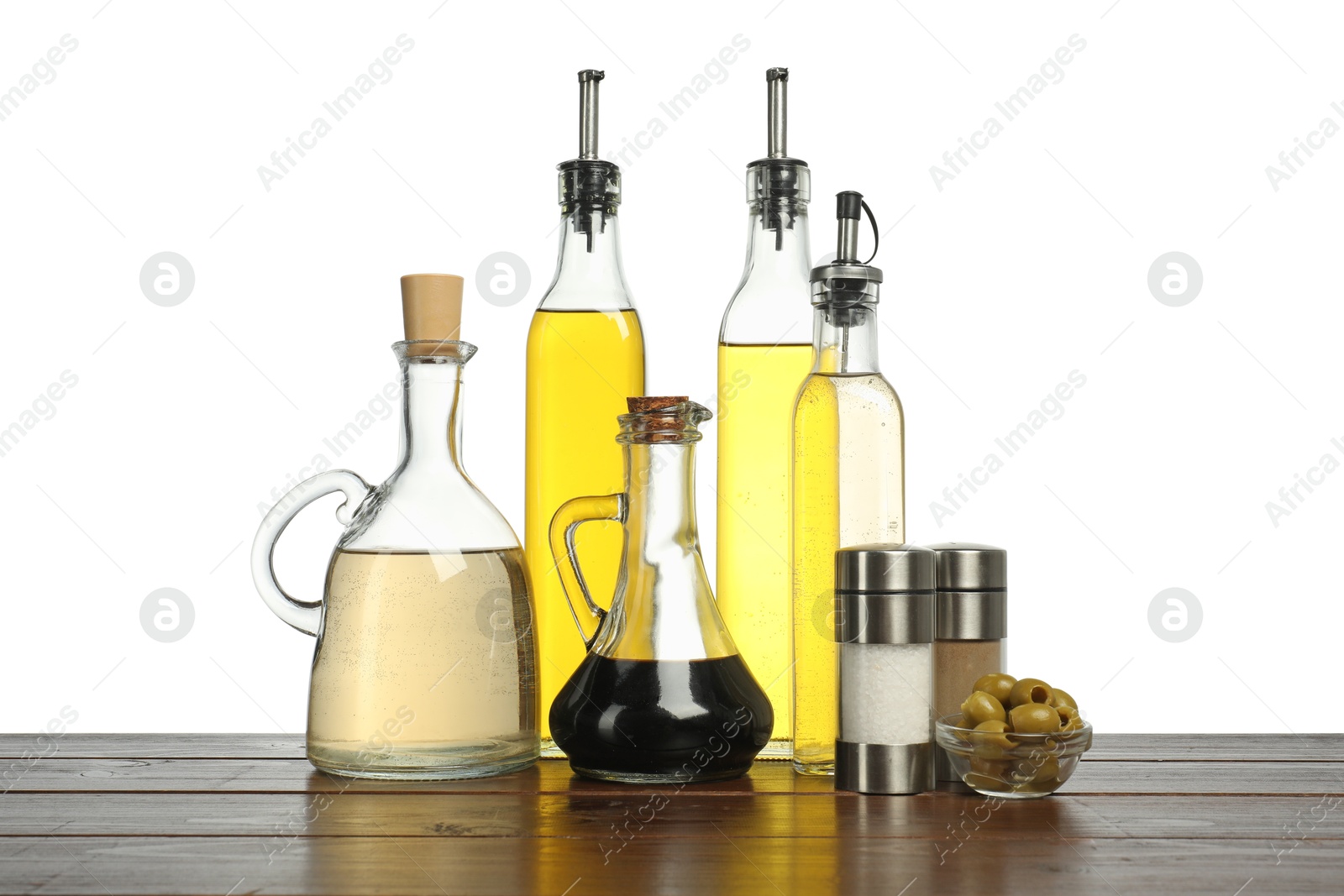 Photo of Salad dressings, olives and spices on wooden table against white background