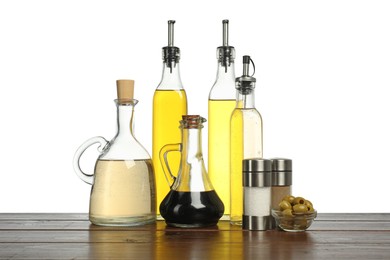 Photo of Salad dressings, olives and spices on wooden table against white background