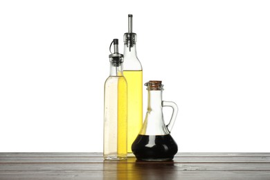 Photo of Oil and vinegars in bottles on wooden table against white background