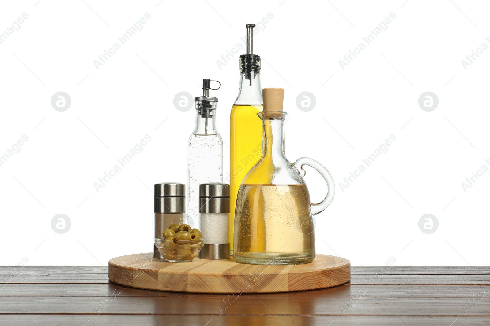 Photo of Salad dressings, olives and spices on wooden table against white background