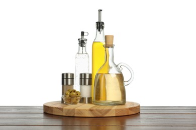 Photo of Salad dressings, olives and spices on wooden table against white background