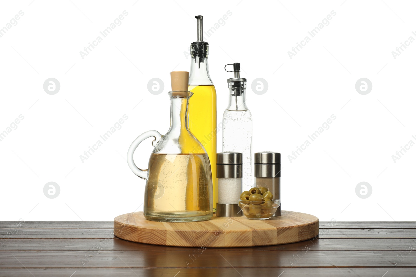 Photo of Salad dressings, olives and spices on wooden table against white background