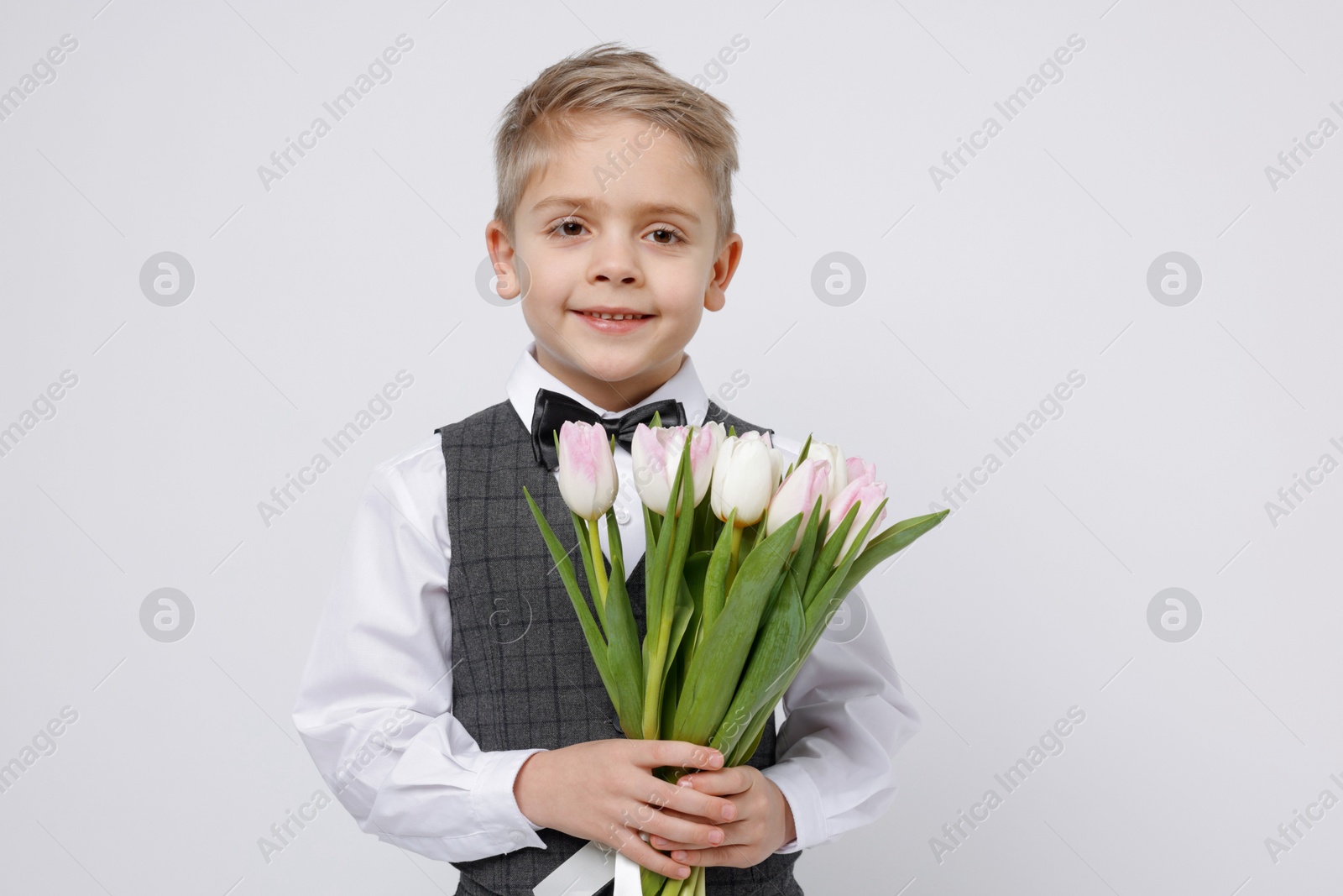 Photo of Cute little boy with bouquet of tulips on white background