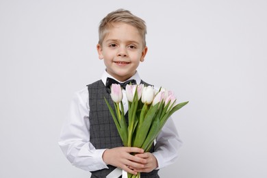 Photo of Cute little boy with bouquet of tulips on white background