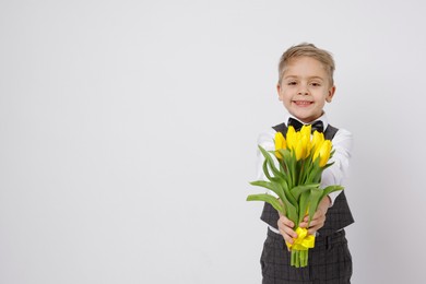 Cute little boy with bouquet of tulips on white background. Space for text