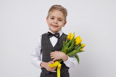 Cute little boy with bouquet of tulips on white background