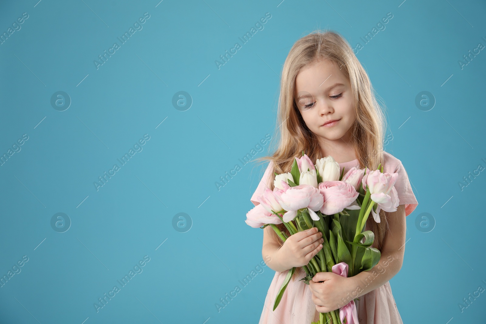 Photo of Cute little girl with bouquet of beautiful spring flowers on light blue background, space for text