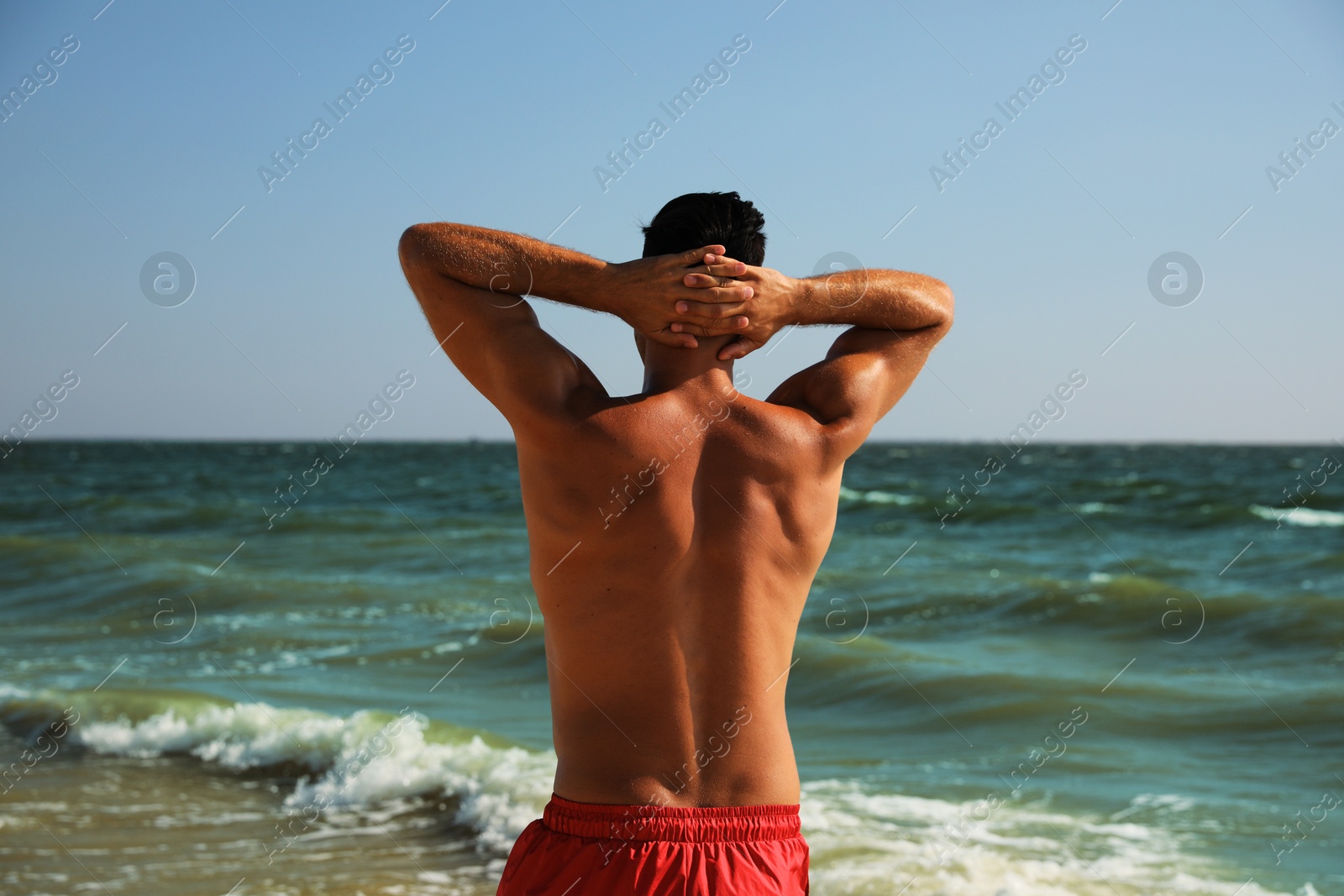 Photo of Man with attractive body on beach, back view