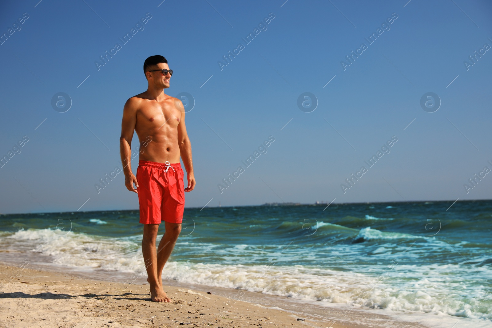 Photo of Handsome man with attractive body on beach. Space for text