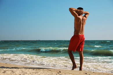 Man with attractive body on beach. Space for text