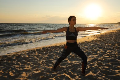 Photo of Young girl with slim body doing yoga on beach