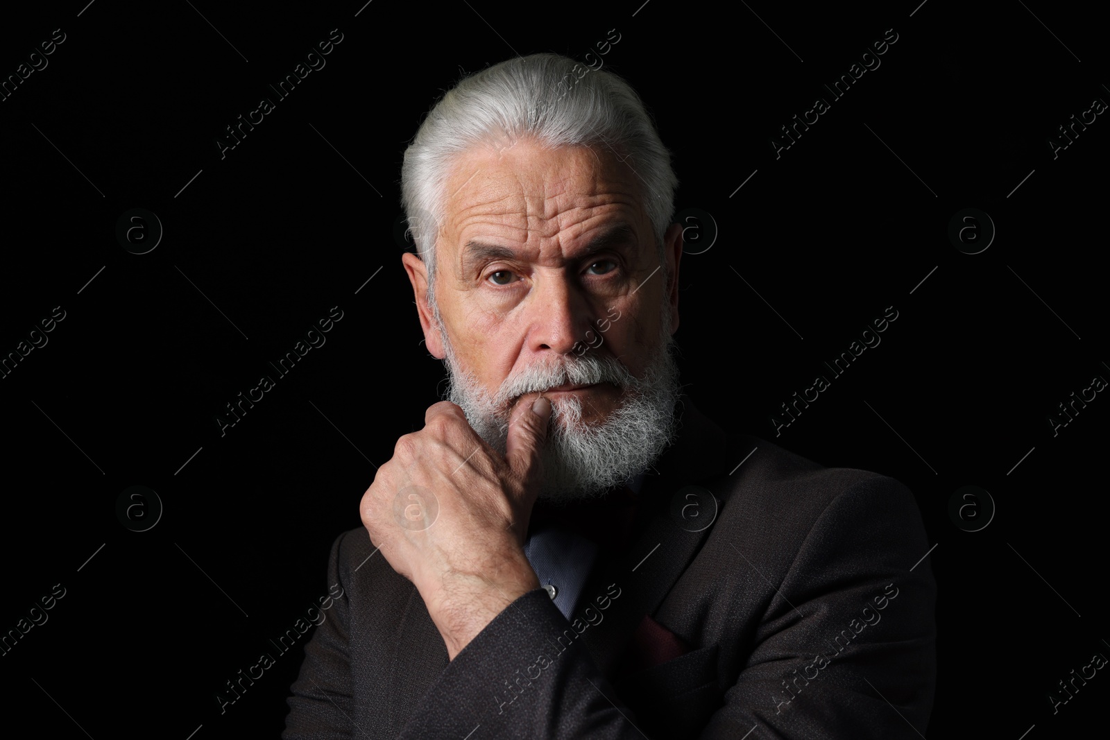 Photo of Portrait of serious senior man with silver beard on black background