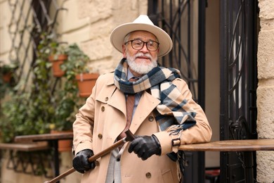 Photo of Stylish senior man with walking cane in outdoor bar