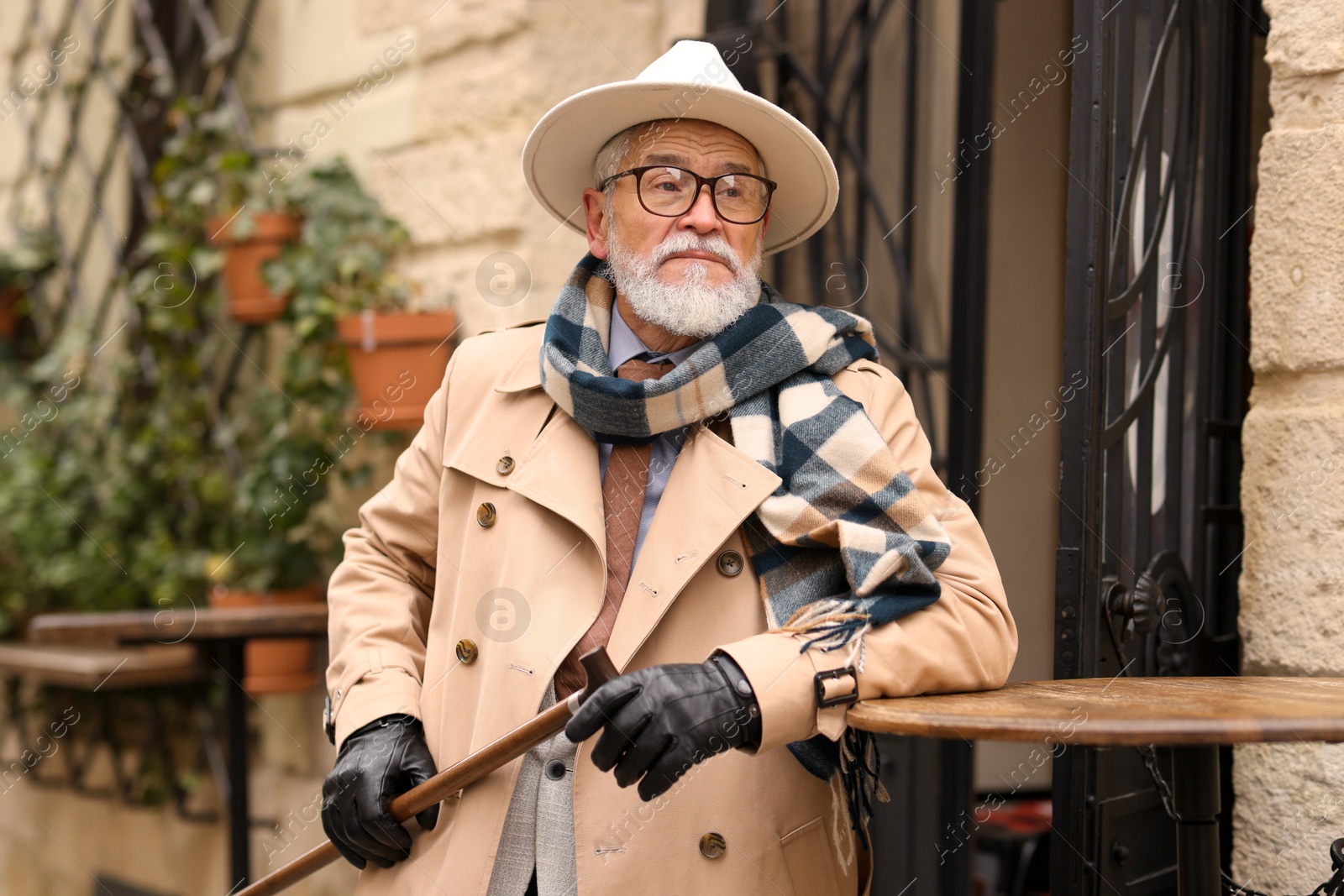 Photo of Stylish senior man with walking cane in outdoor bar