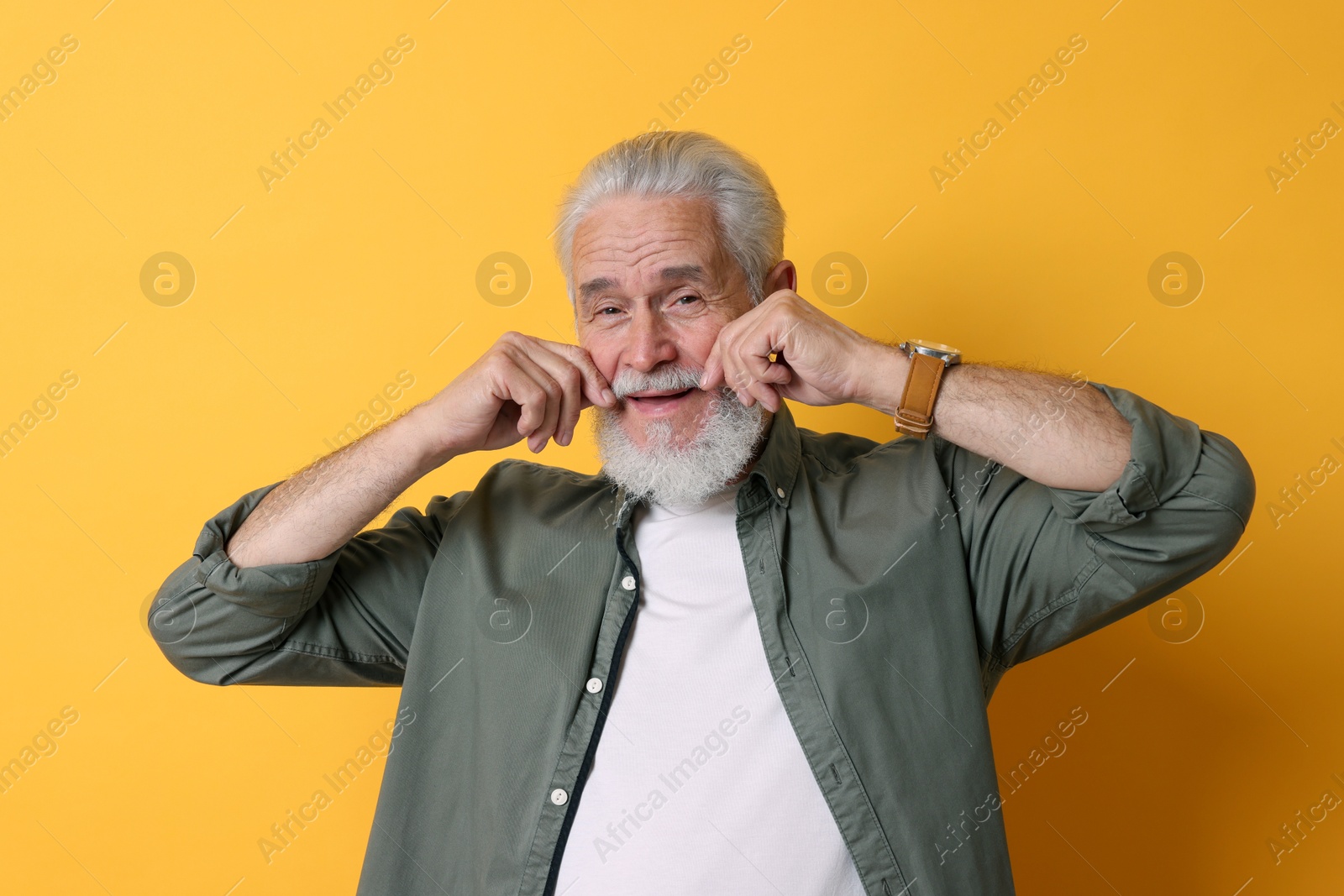 Photo of Portrait of senior man with gray beard on orange background