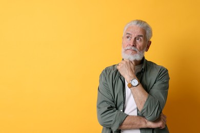 Photo of Portrait of senior man with gray beard on orange background. Space for text