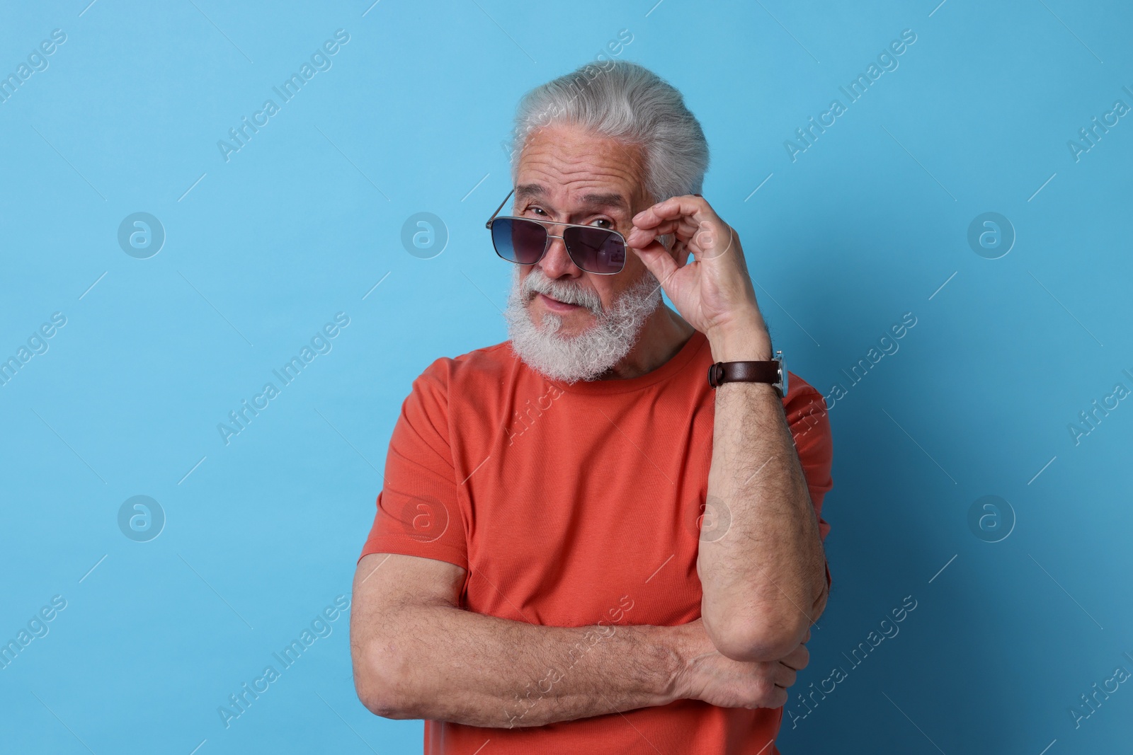 Photo of Senior man in sunglasses on light blue background