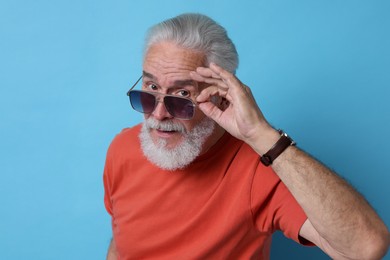 Photo of Senior man in sunglasses on light blue background