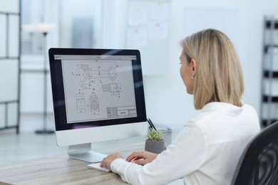 Photo of Technician making digital engineering drawing on computer at desk in office