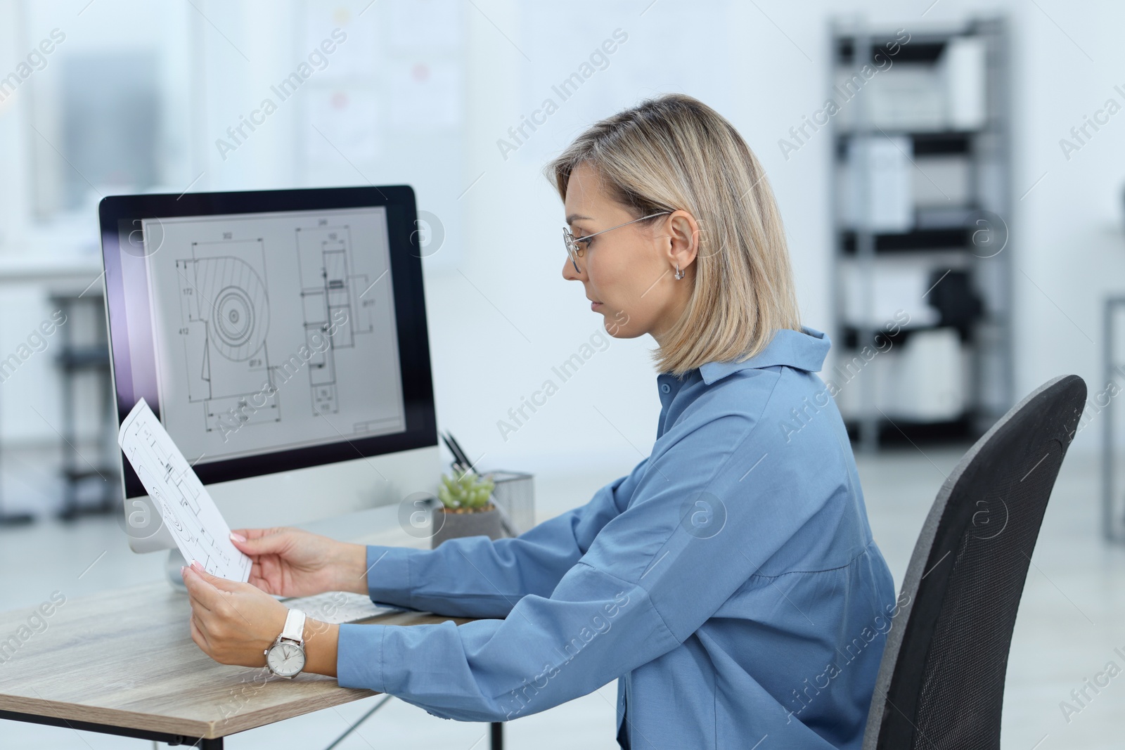 Photo of Technician making digital engineering drawing on computer at desk in office