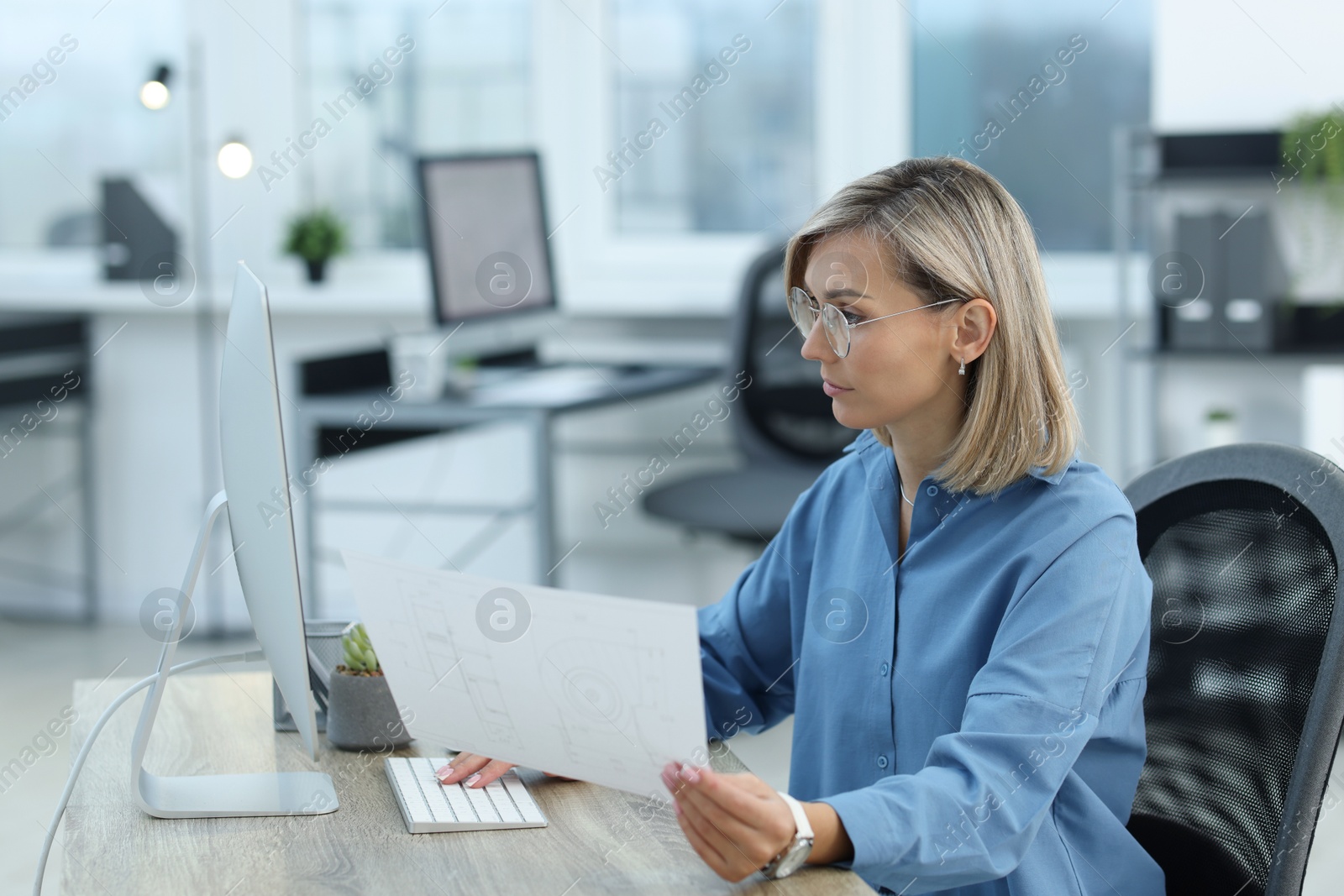 Photo of Technician making digital engineering drawing on computer at desk in office