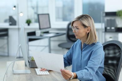 Photo of Technician making digital engineering drawing on computer at desk in office